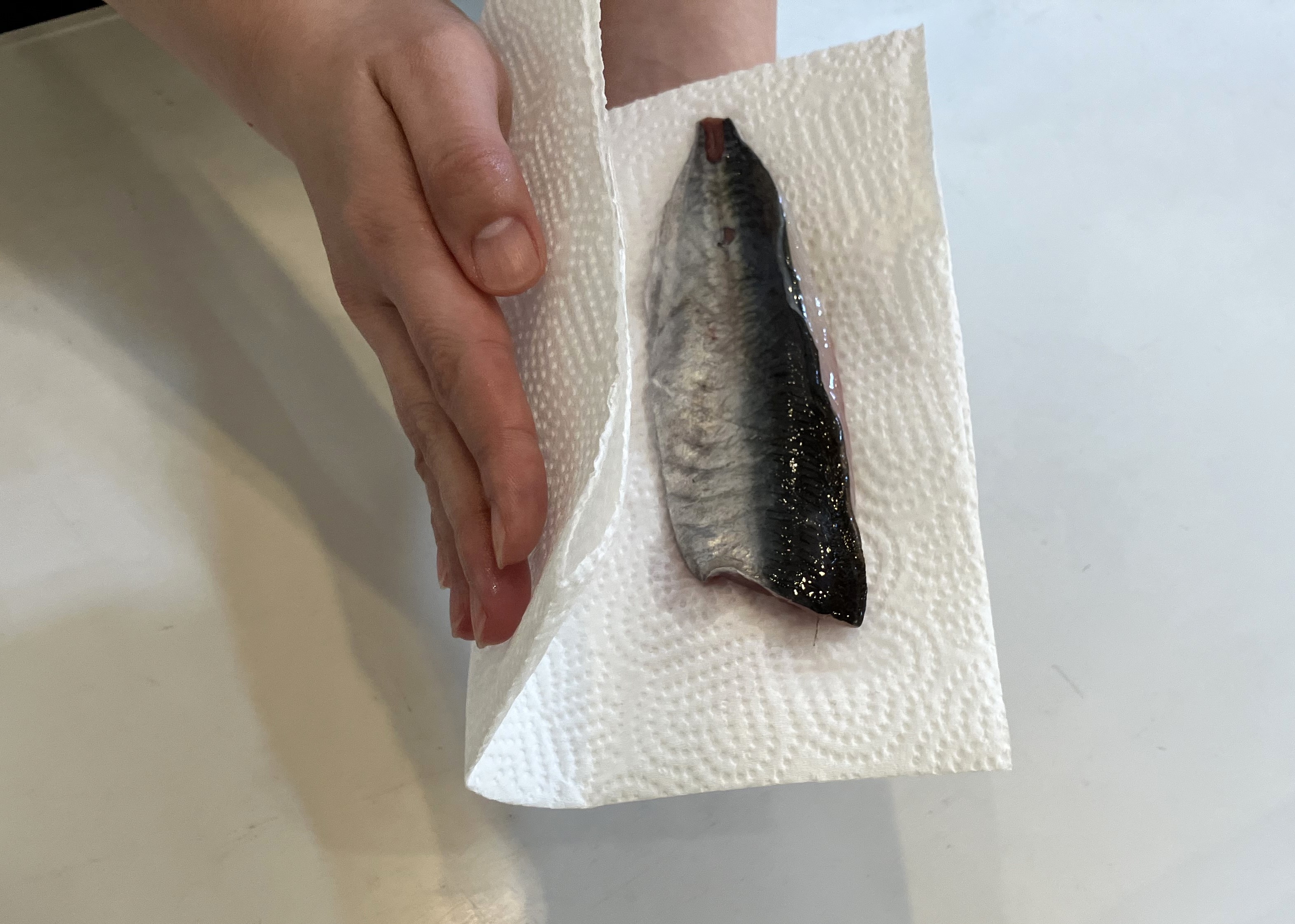 2. 魚の開きや切り身の表面の水分をキッチンペーパーで完全にふき取り、新しいキッチンペーパーで包みましょう