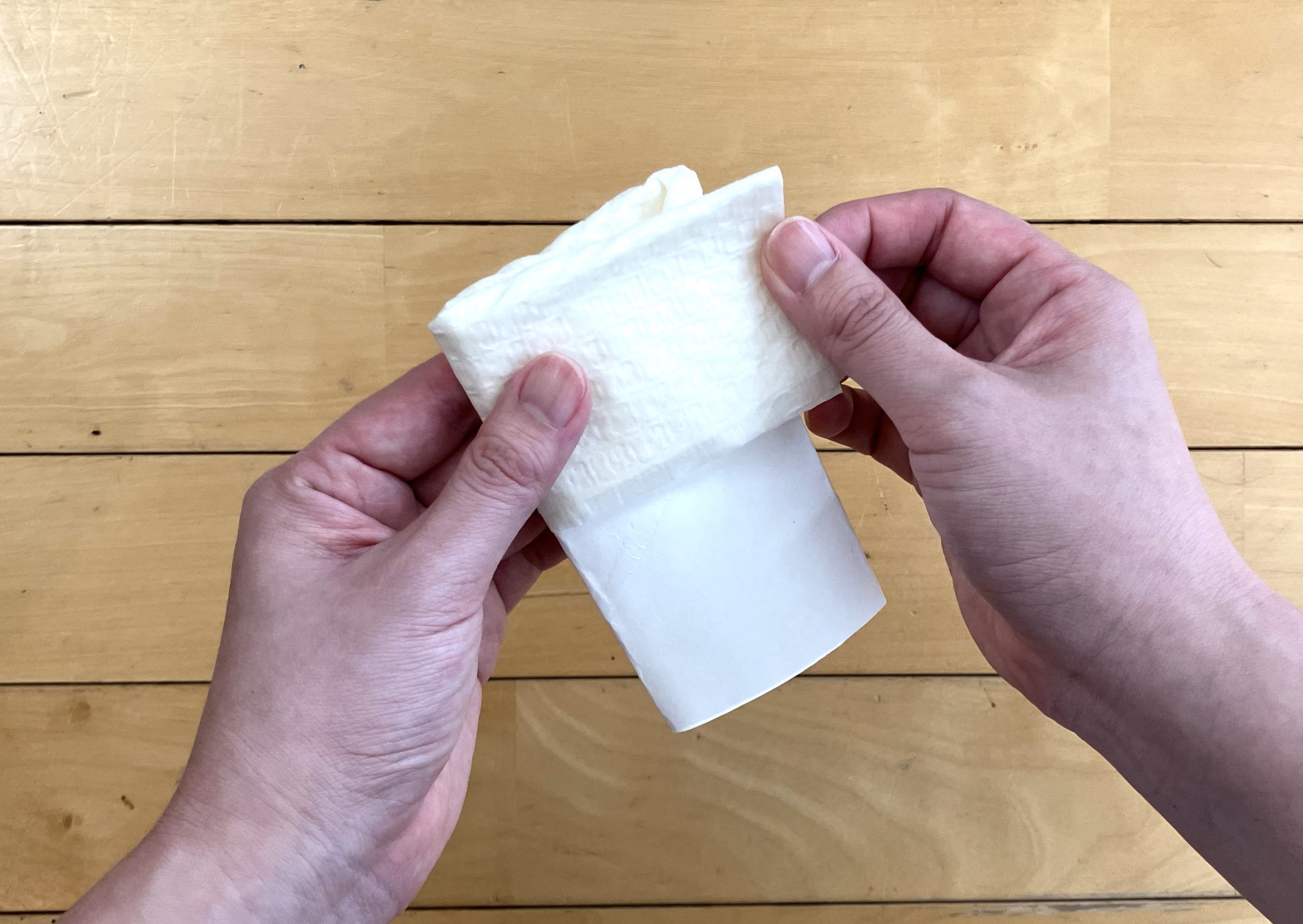 2. つぶしたトイレットペーパーの芯の片方の端にトイレ用クリーナーを巻きつけ、指で押さえて持ちやすい形にしましょう。