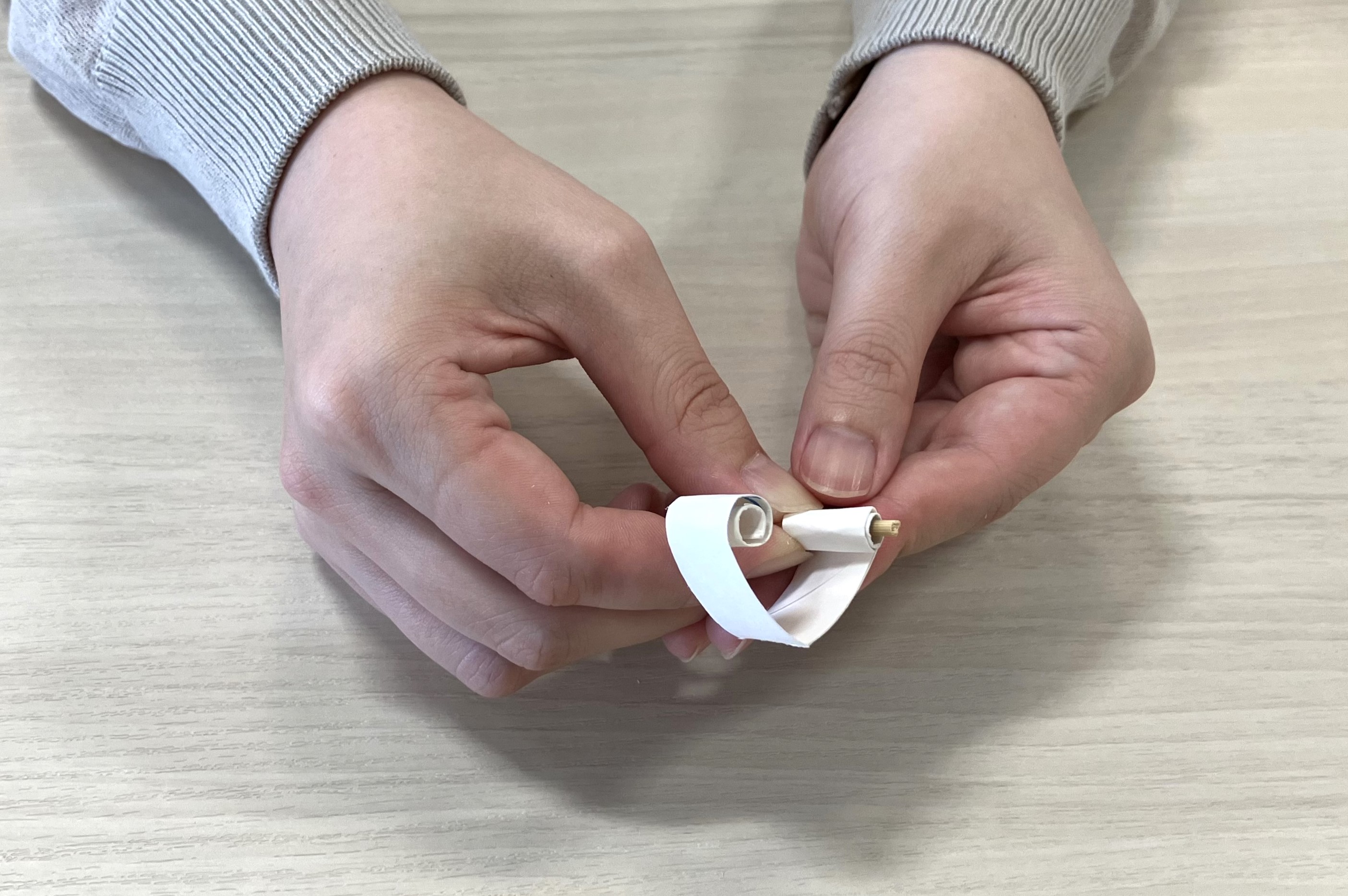輪っかを開き、両端をそれぞれ3cm程度、内側に向かって巻いてください